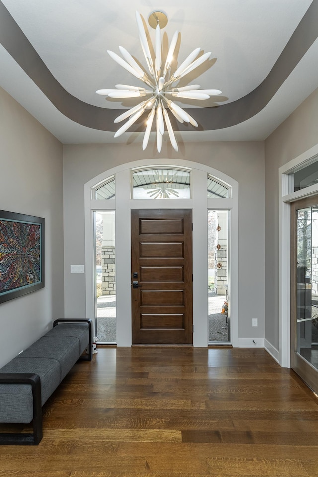 foyer entrance with wood finished floors and a chandelier