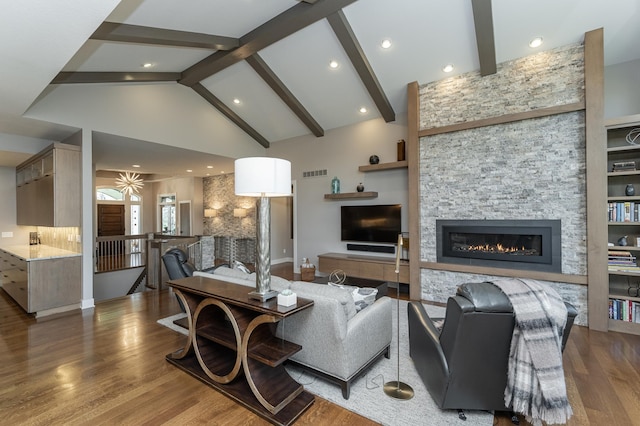 living room with visible vents, beamed ceiling, high vaulted ceiling, wood finished floors, and a stone fireplace