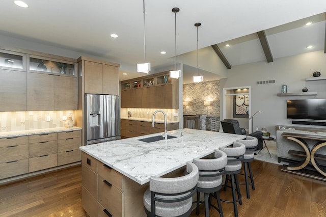 kitchen featuring a sink, dark wood-type flooring, stainless steel refrigerator with ice dispenser, a kitchen bar, and modern cabinets