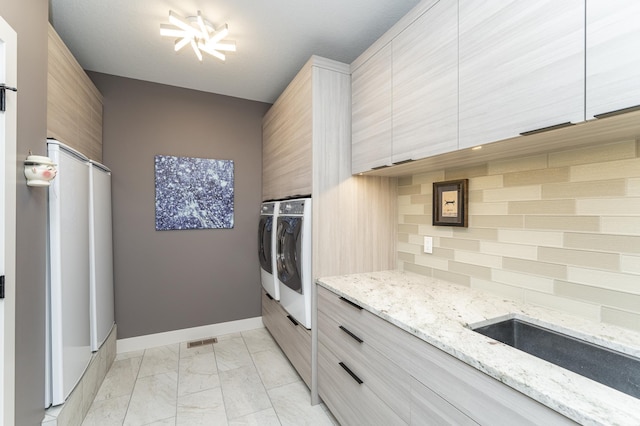 kitchen with washing machine and clothes dryer, backsplash, baseboards, marble finish floor, and modern cabinets