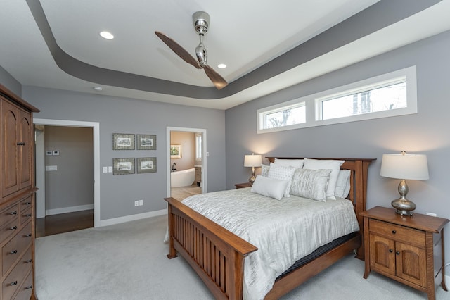 bedroom featuring recessed lighting, a tray ceiling, baseboards, and light colored carpet