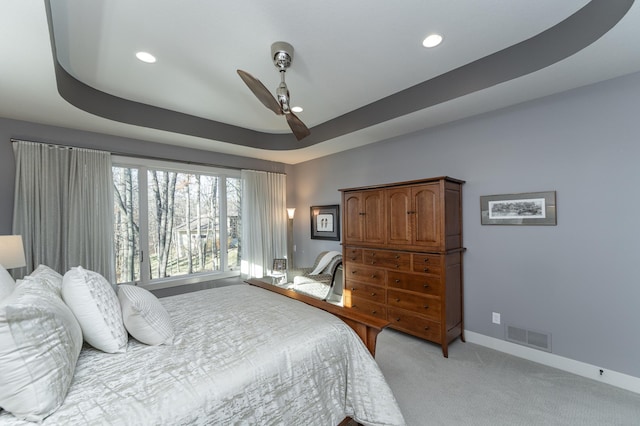 bedroom featuring visible vents, baseboards, a tray ceiling, light carpet, and recessed lighting