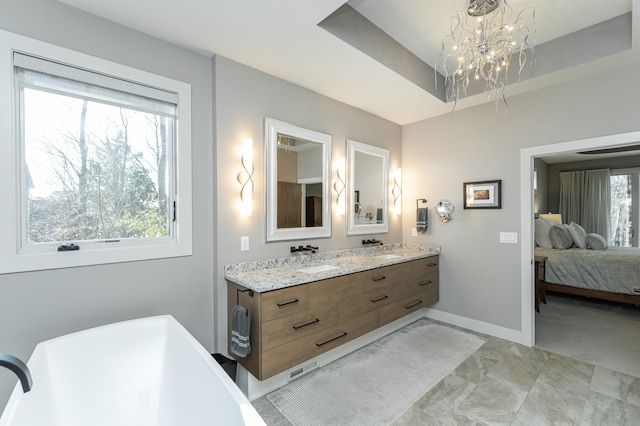 bathroom with a chandelier, plenty of natural light, a raised ceiling, and a freestanding tub