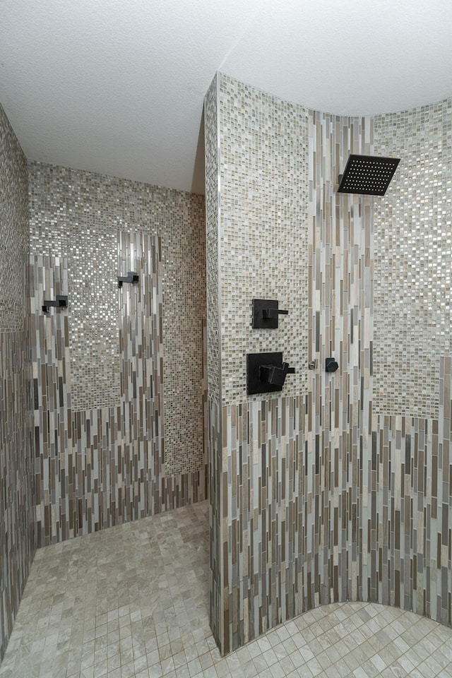 full bath featuring a textured ceiling and a tile shower