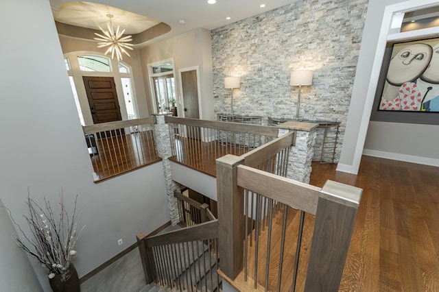 staircase with recessed lighting, baseboards, an inviting chandelier, and wood finished floors