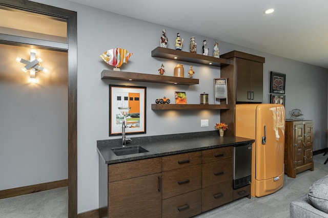 kitchen with a sink, open shelves, light carpet, and dark countertops