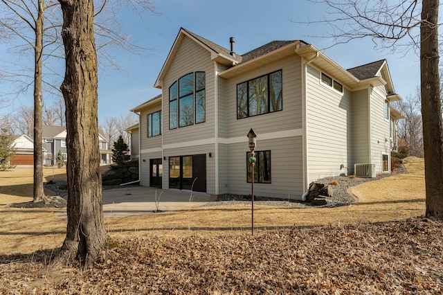 rear view of house with central air condition unit, concrete driveway, and a patio