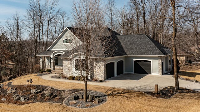 view of front of home featuring a porch, concrete driveway, roof with shingles, stone siding, and an attached garage