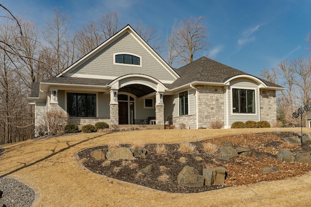 view of front of home with stone siding and roof with shingles