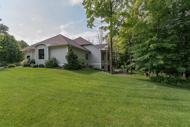 view of side of home featuring a lawn and roof with shingles