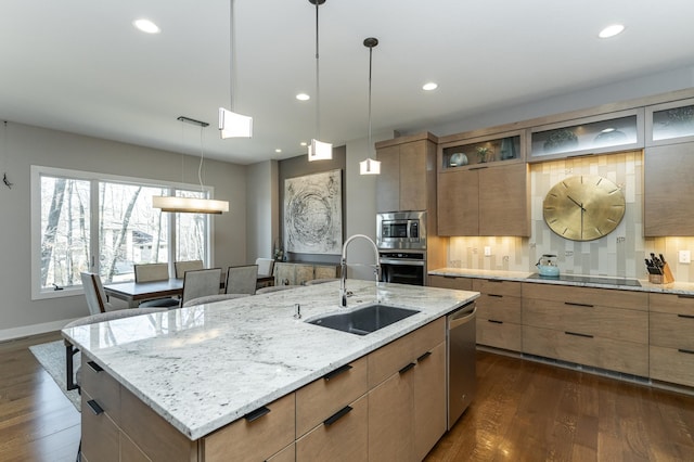 kitchen with a sink, modern cabinets, dark wood finished floors, stainless steel appliances, and an island with sink