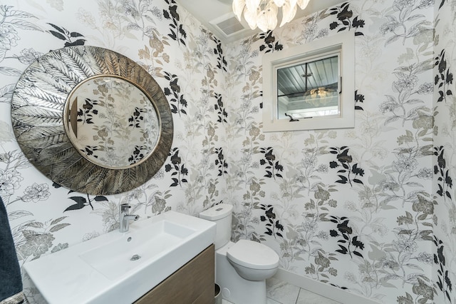 bathroom with wallpapered walls, toilet, vanity, and a chandelier