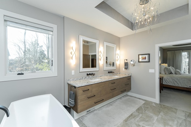 full bathroom with a chandelier, a freestanding bath, baseboards, ensuite bathroom, and double vanity