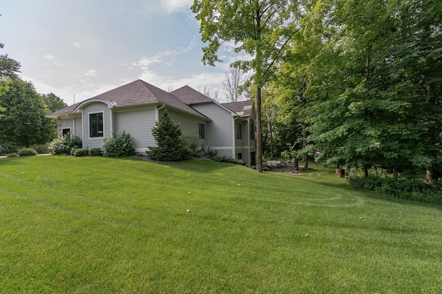 view of home's exterior with a lawn and roof with shingles