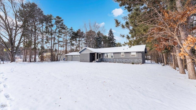 snow covered rear of property featuring a garage