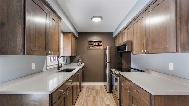 kitchen featuring dark brown cabinets, stainless steel appliances, sink, and light hardwood / wood-style flooring