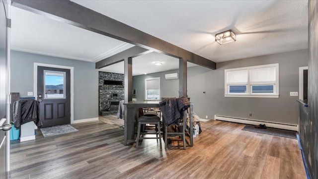 dining room with hardwood / wood-style flooring, beam ceiling, a wall mounted AC, and a baseboard heating unit