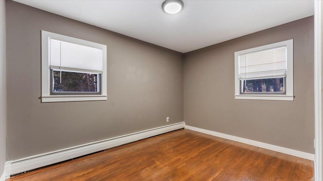 unfurnished room featuring hardwood / wood-style floors and a baseboard heating unit