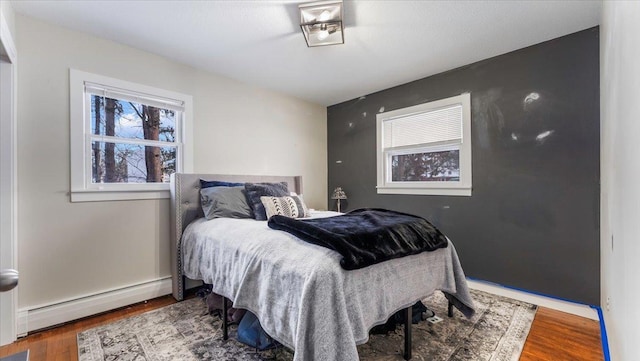 bedroom featuring a baseboard heating unit and dark wood-type flooring