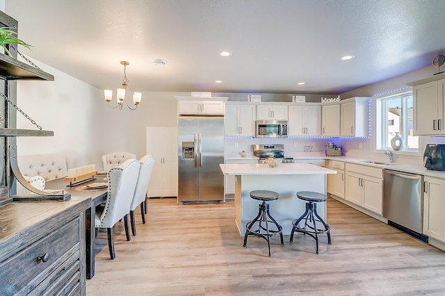 kitchen featuring sink, a center island, light hardwood / wood-style flooring, pendant lighting, and stainless steel appliances