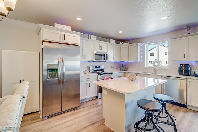 kitchen featuring stainless steel appliances, a breakfast bar, white cabinets, and a kitchen island