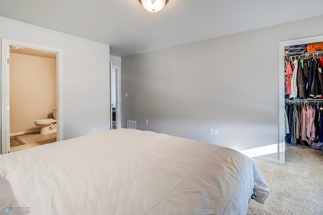 bedroom with ensuite bathroom, carpet flooring, and a closet