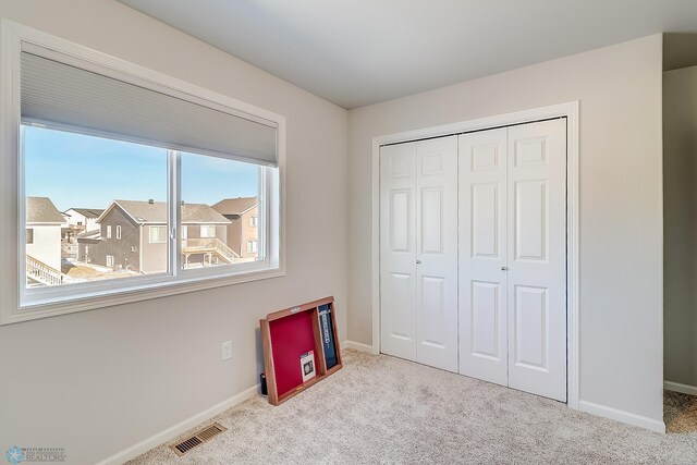 unfurnished bedroom featuring light carpet and a closet