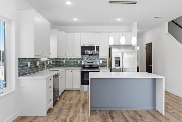 kitchen with sink, white cabinets, hanging light fixtures, a center island, and stainless steel appliances