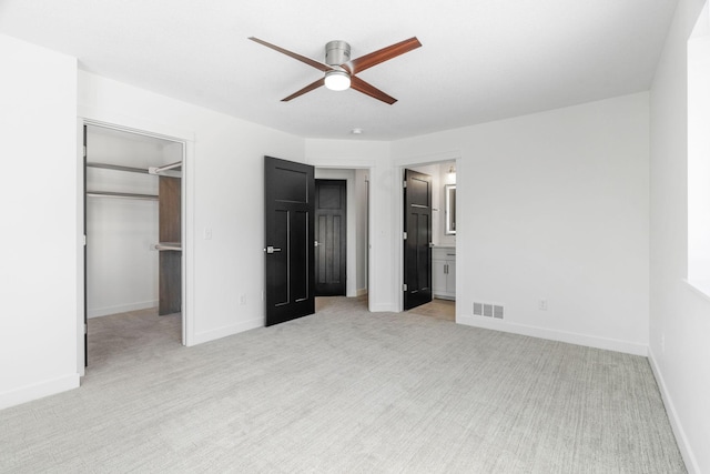 unfurnished bedroom with ceiling fan, connected bathroom, light carpet, a spacious closet, and a closet