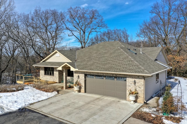 view of front of house with a garage, roof with shingles, driveway, and brick siding