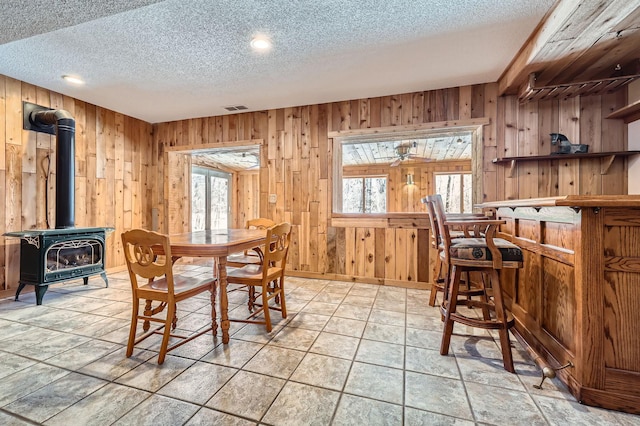 10740 230th St N, Scandia, MN 55073 - dining space featuring a textured ceiling, a wood stove, wood walls, a dry bar, and recessed lighting