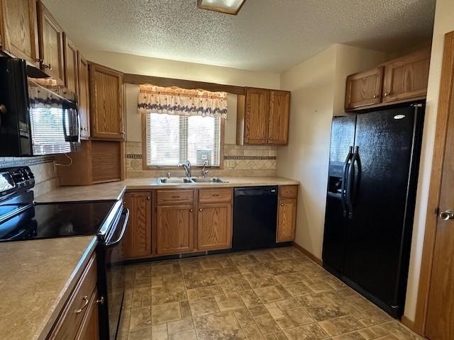 kitchen featuring tasteful backsplash, sink, black appliances, and a textured ceiling