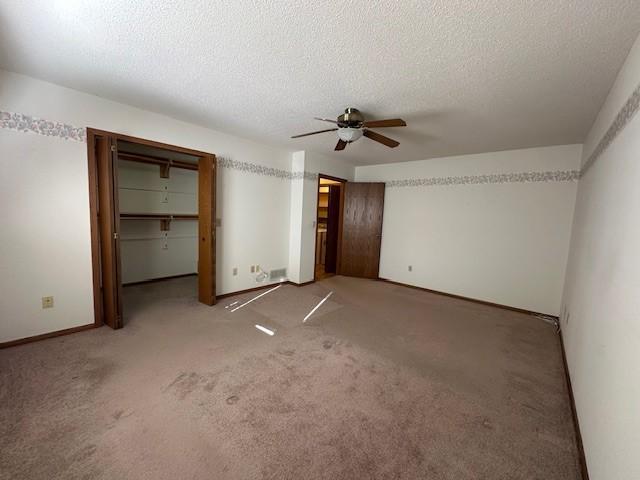 unfurnished bedroom with ceiling fan, carpet, and a textured ceiling