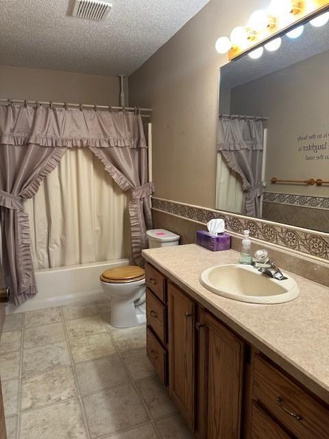 full bathroom featuring vanity, shower / tub combo, a textured ceiling, and toilet