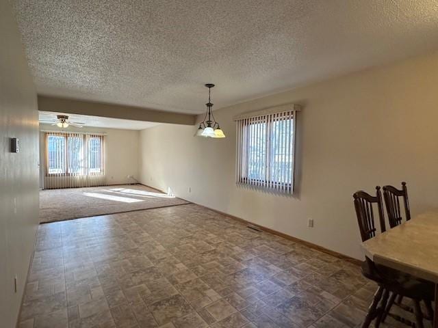 unfurnished dining area featuring a textured ceiling and ceiling fan