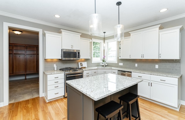 3942 Autumn Lake Ct SW, Rochester, MN 55902 - kitchen featuring appliances with stainless steel finishes, white cabinetry, a center island, a kitchen bar, and crown molding