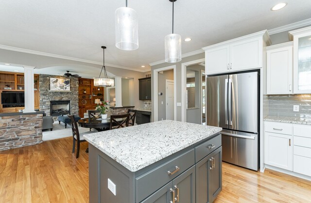 3942 Autumn Lake Ct SW, Rochester, MN 55902 - kitchen featuring freestanding refrigerator, a fireplace, ornamental molding, white cabinets, and light wood-type flooring