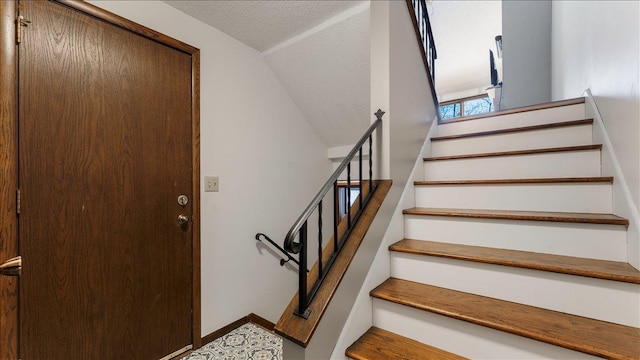 stairway with lofted ceiling, baseboards, and a textured ceiling