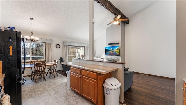 kitchen featuring light countertops, lofted ceiling, brown cabinets, freestanding refrigerator, and a textured ceiling