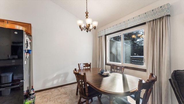 dining room featuring a notable chandelier, lofted ceiling, and baseboards