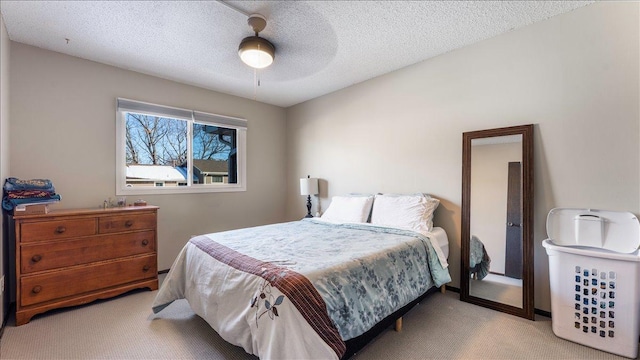 bedroom featuring light colored carpet, a ceiling fan, and a textured ceiling