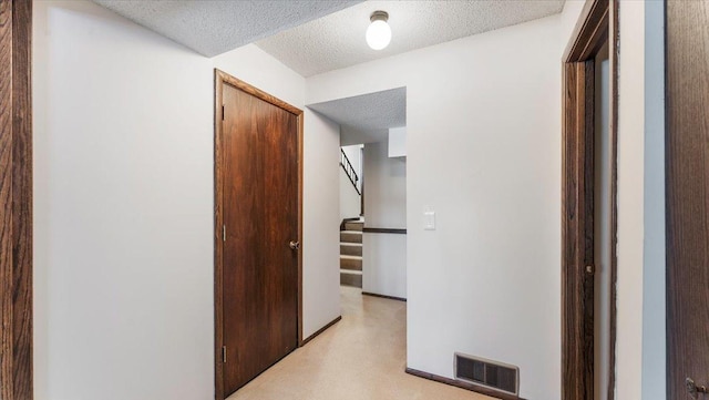 hallway featuring stairway, visible vents, and a textured ceiling