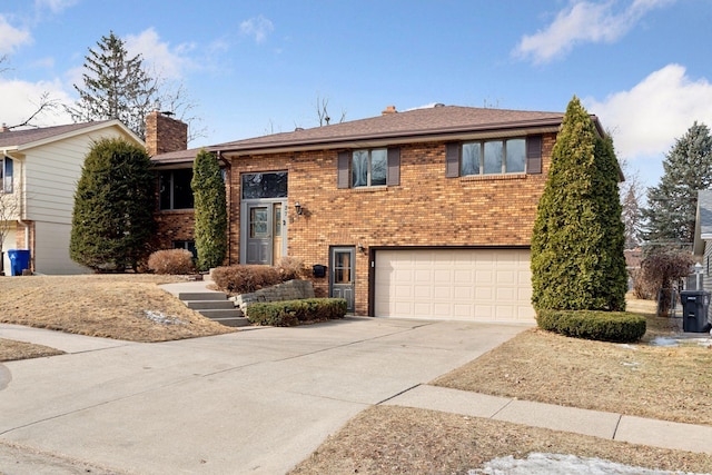 view of front of property with driveway, brick siding, a chimney, and an attached garage