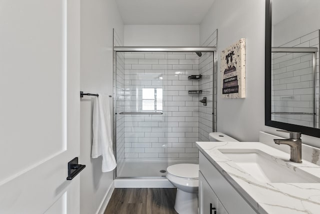 bathroom featuring vanity, an enclosed shower, hardwood / wood-style flooring, and toilet