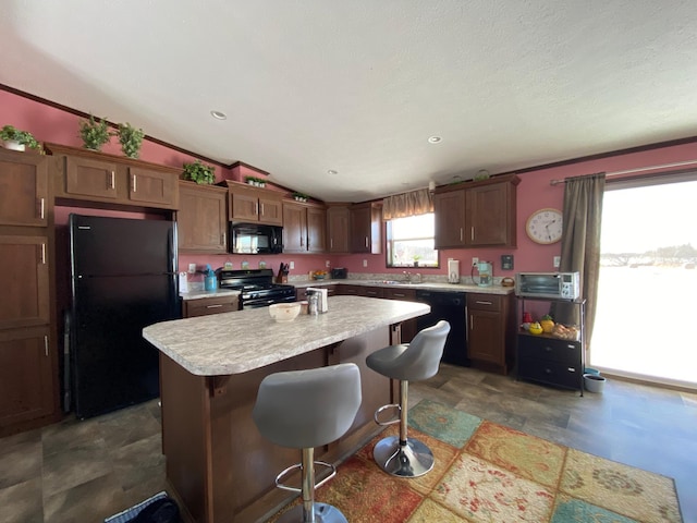 kitchen with lofted ceiling, a breakfast bar, a kitchen island, and black appliances