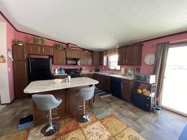 kitchen with sink, a kitchen breakfast bar, a center island, black appliances, and vaulted ceiling