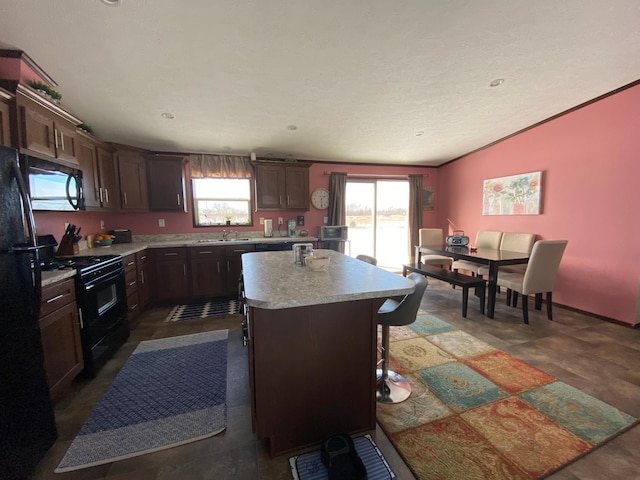 kitchen with a healthy amount of sunlight, a center island, sink, and black appliances