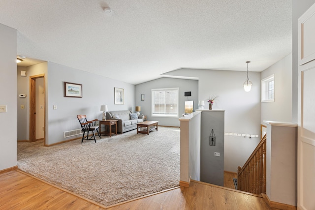 living room with vaulted ceiling, plenty of natural light, hardwood / wood-style floors, and a textured ceiling