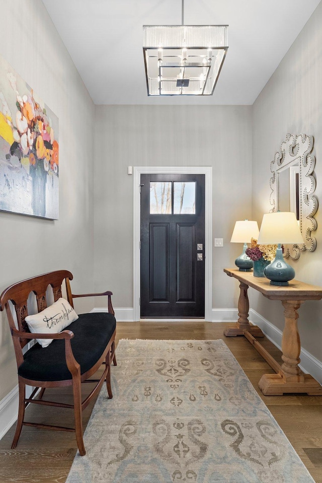 foyer featuring a notable chandelier, baseboards, and wood finished floors