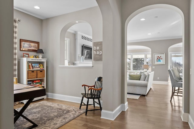 corridor featuring crown molding, baseboards, wood finished floors, and recessed lighting